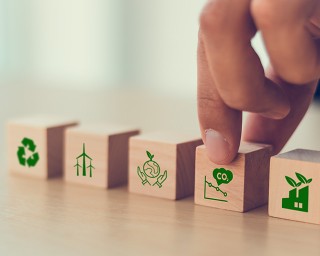 Net-Zero-Konzept und Konzept zur CO2-Neutralität. Ziel: Net-Zero-Treibhausgasemissionen. Klimaneutrale Langzeitstrategie. Von Hand aufgestellte Holzwürfel mit Symbol für Recycling, Windenergie, Klimaschutz, für die Verringerung der Kohlenstoffemissionen. 